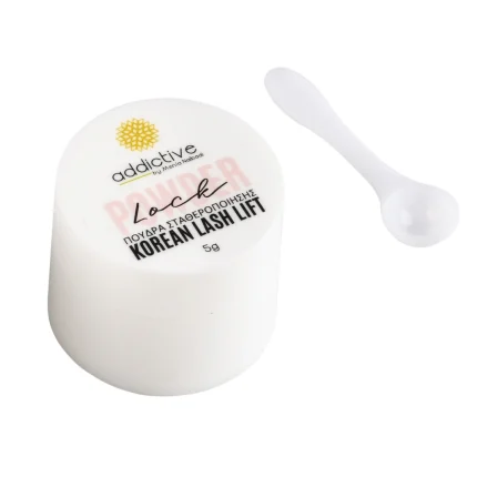 Λευκό βαζάκι της πούδρας σταθεροποίησης Powder Lock (5g) της Addictive Lashes, ειδική για την τεχνική Korean Lash Lift, φωτογραφημένη δίπλα στο λευκό κουταλάκι εφαρμογής.