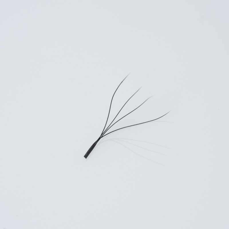 Κοντινή λήψη (macro) ενός έτοιμου fan βλεφαρίδων (premade fan) 4D, αποτελούμενου από 4 λεπτές, μαύρες ίνες ενωμένες στη βάση με μακρύ κορμό (long stem), για τεχνική volume.