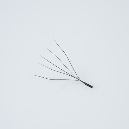 Κοντινή λήψη (macro) ενός έτοιμου pre made fan βλεφαρίδων (premade fan) 5D, αποτελούμενου από 5 λεπτές, μαύρες ίνες ενωμένες στη βάση με μακρύ κορμό (long stem), κατάλληλο για τεχνική volume extensions.